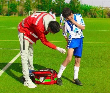 Secouriste soignant un jeune footballeur sur un terrain